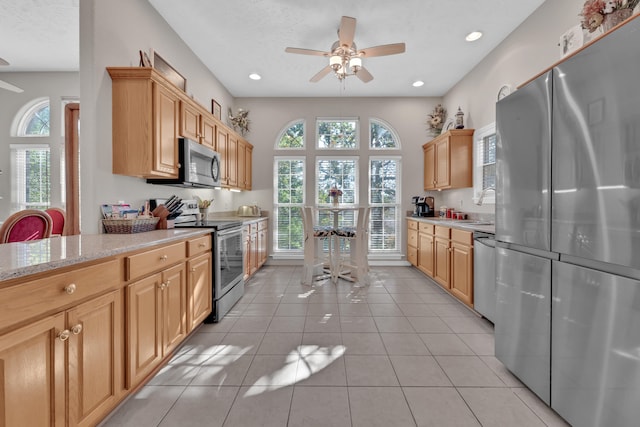 kitchen featuring light tile patterned floors, light stone countertops, plenty of natural light, and stainless steel appliances