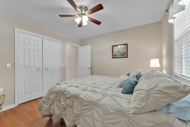 bedroom with light wood-type flooring, ceiling fan, a closet, and a textured ceiling