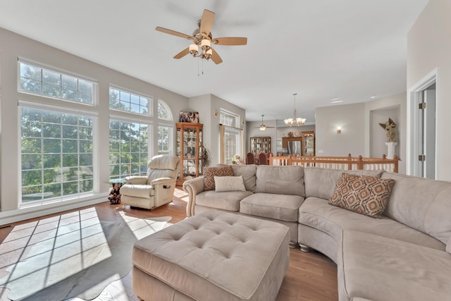 living room with ceiling fan with notable chandelier and light hardwood / wood-style floors