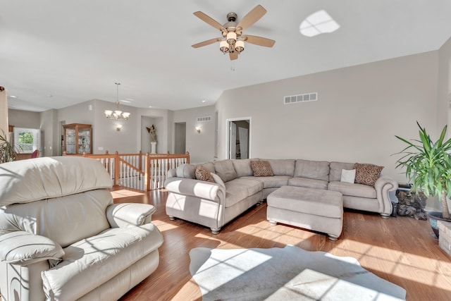 living room featuring ceiling fan with notable chandelier and light hardwood / wood-style flooring