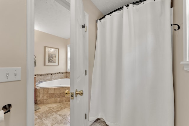 bathroom featuring a relaxing tiled tub and a textured ceiling