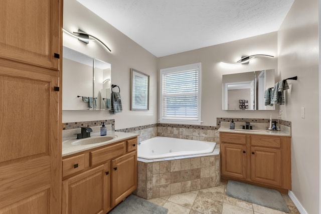 bathroom featuring tiled tub, vanity, and a textured ceiling