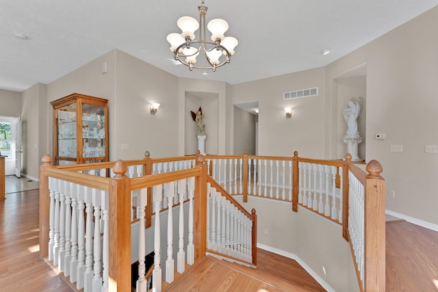 stairs featuring hardwood / wood-style floors and an inviting chandelier