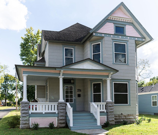 victorian house featuring a front lawn and a porch