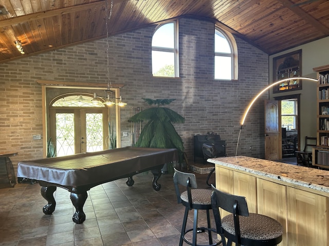 playroom with brick wall, a wood stove, french doors, and wood ceiling