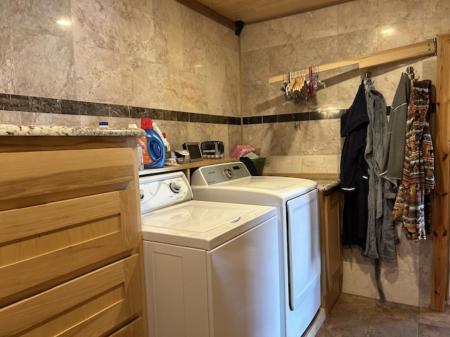 clothes washing area with tile walls, washing machine and clothes dryer, and laundry area