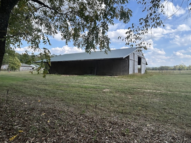 view of property exterior featuring a pole building, an outdoor structure, metal roof, and a lawn