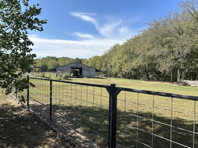 view of yard featuring an outbuilding, fence, a garage, and a rural view