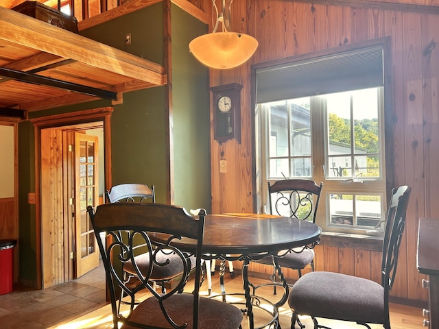 tiled dining room with wood walls and beam ceiling