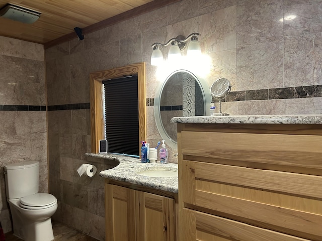 full bath with toilet, visible vents, tile walls, and vanity