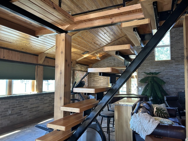 stairway with wood ceiling, brick wall, and vaulted ceiling with beams