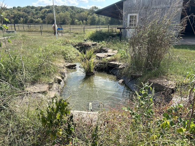 property view of water featuring a view of trees and fence