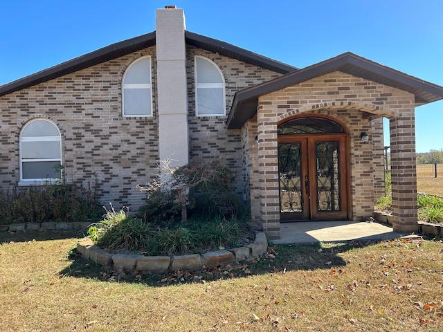 view of exterior entry with a yard and french doors