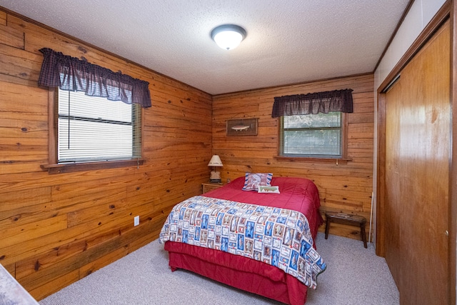 carpeted bedroom with a textured ceiling, a closet, and wood walls