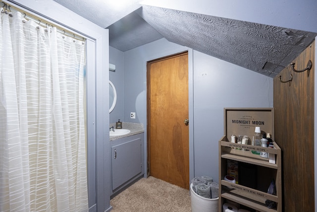 bathroom with vanity, vaulted ceiling, and a textured ceiling