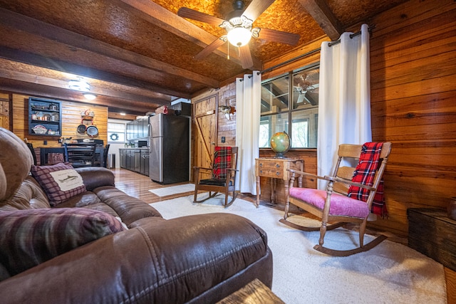 living room with wood walls, beamed ceiling, and ceiling fan