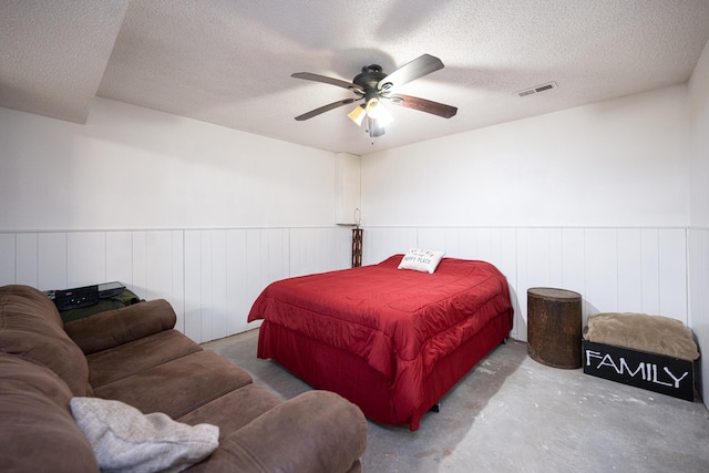 bedroom with ceiling fan, a textured ceiling, and concrete floors