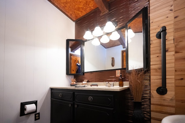 bathroom with wooden walls, vanity, and beamed ceiling