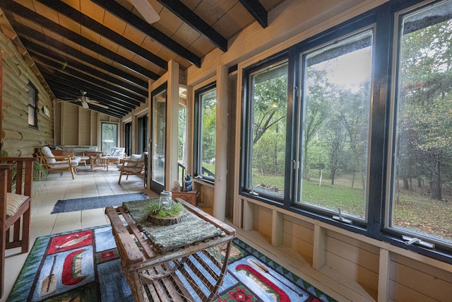 unfurnished sunroom featuring ceiling fan, a healthy amount of sunlight, and vaulted ceiling with beams