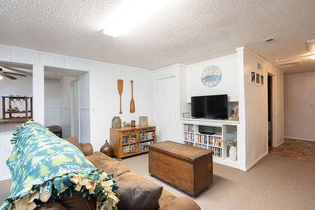 carpeted living room with ceiling fan and a textured ceiling