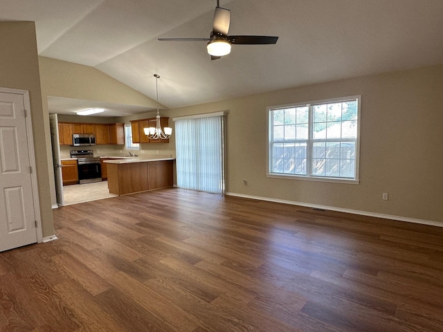 unfurnished living room with ceiling fan with notable chandelier, vaulted ceiling, and dark hardwood / wood-style flooring