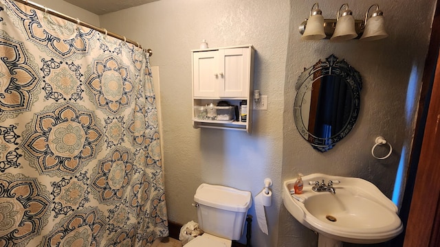 bathroom featuring a shower with curtain, sink, and toilet