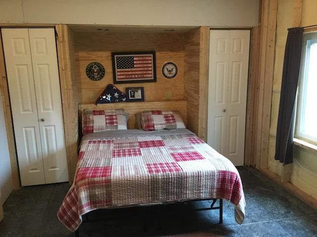 bedroom with wood walls and two closets