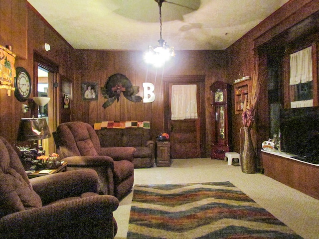 living room with carpet, wooden walls, and an inviting chandelier