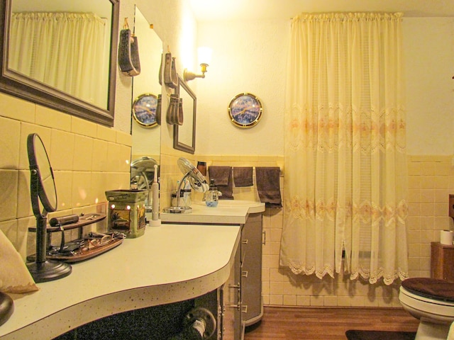 bathroom featuring toilet, tile walls, wainscoting, wood finished floors, and vanity