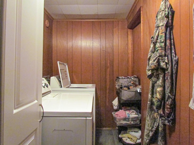 laundry room with wooden walls, washer and dryer, and laundry area