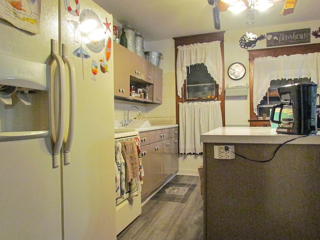 kitchen featuring a sink, white refrigerator with ice dispenser, light countertops, backsplash, and dark wood-style flooring