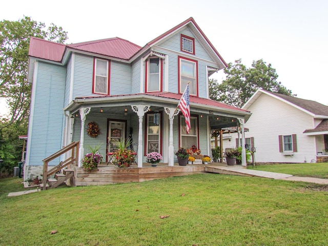 victorian-style house featuring covered porch, a front yard, and metal roof