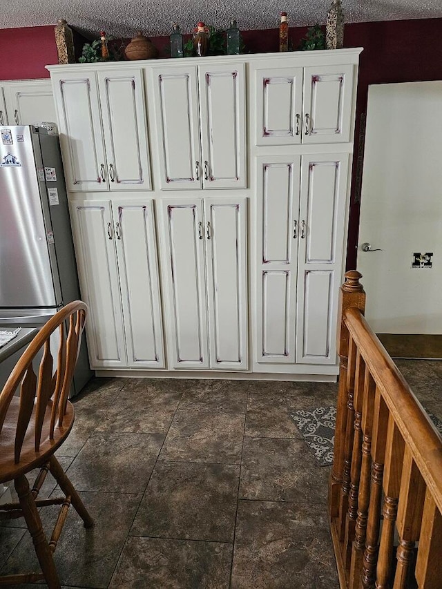 kitchen with a textured ceiling and white cabinetry