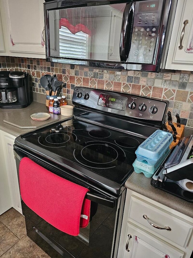 kitchen with tasteful backsplash, black range with electric stovetop, tile patterned flooring, and white cabinets