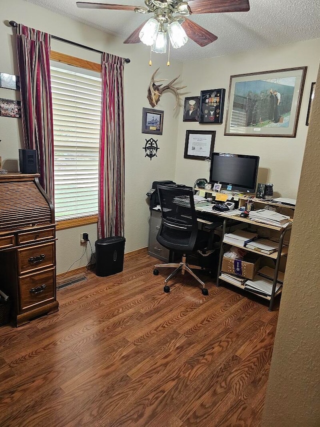 home office featuring ceiling fan, dark wood-type flooring, and a textured ceiling