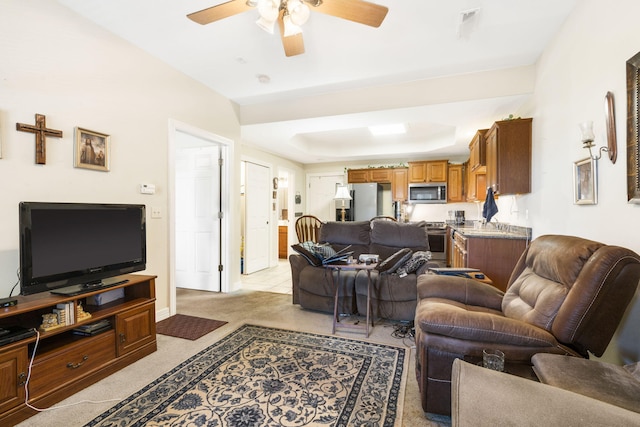 carpeted living room featuring ceiling fan and a raised ceiling