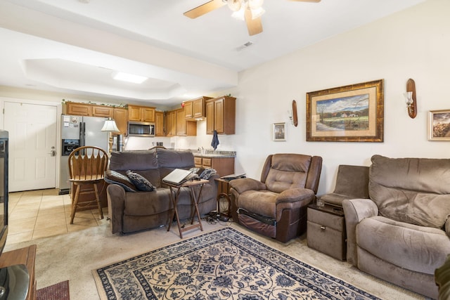 tiled living room with ceiling fan and a raised ceiling