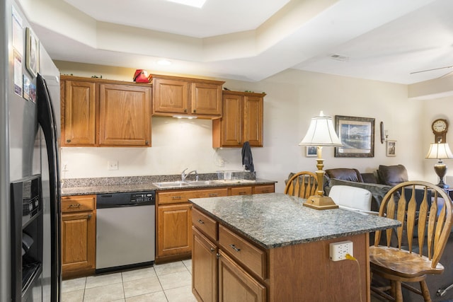 kitchen with a kitchen island, stainless steel appliances, sink, light tile patterned flooring, and a tray ceiling