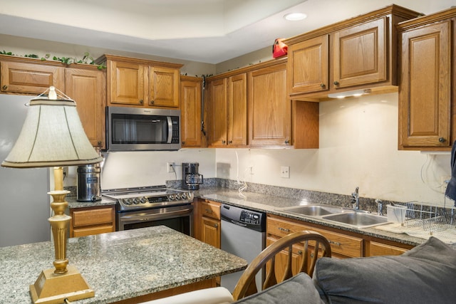 kitchen with appliances with stainless steel finishes, light stone countertops, and sink