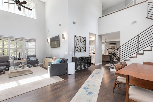 living room with a high ceiling, ceiling fan, a wealth of natural light, and dark wood-type flooring