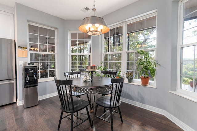 dining space featuring an inviting chandelier, plenty of natural light, and dark wood-type flooring