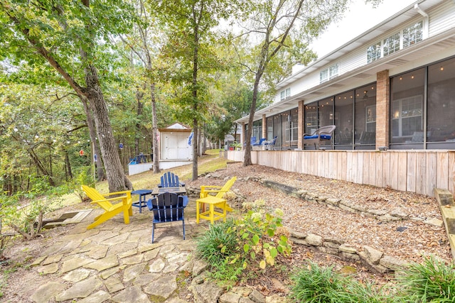 view of patio / terrace with a sunroom and a storage unit