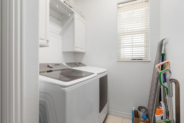 washroom with cabinets, plenty of natural light, washing machine and clothes dryer, and light tile patterned flooring