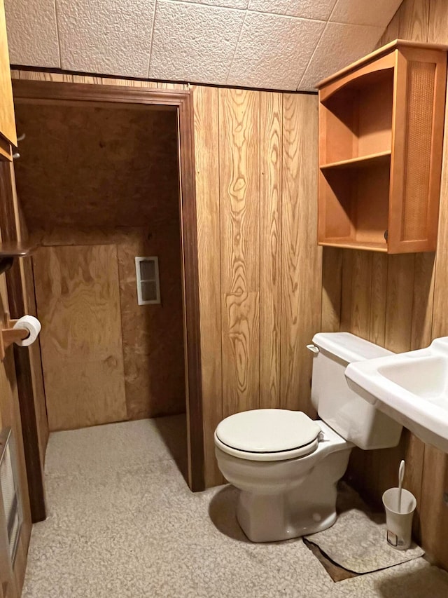 bathroom with toilet and wood walls