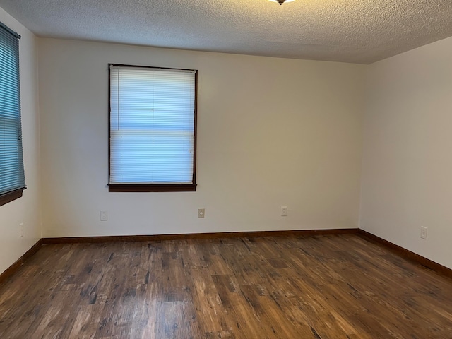 empty room featuring a textured ceiling and dark hardwood / wood-style floors