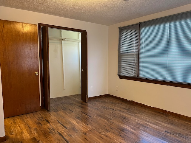 unfurnished bedroom featuring dark wood-type flooring, a textured ceiling, and a closet