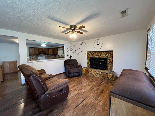 living room featuring ceiling fan, hardwood / wood-style flooring, a textured ceiling, and a fireplace