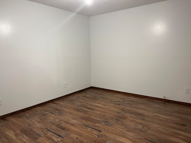 unfurnished room with dark wood-type flooring and a textured ceiling