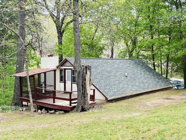 rear view of house featuring a wooden deck, roof with shingles, and a yard