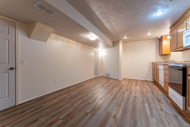 interior space featuring white appliances, light brown cabinetry, a textured ceiling, and light hardwood / wood-style floors